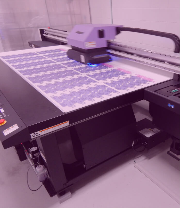 Detalhe da impressora digital imprimindo etiquetas técnicas em policarbonato.